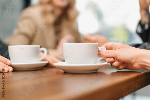 Fototapeta A cup of filter coffee on a table in a coffee shop, a noisy group of friends