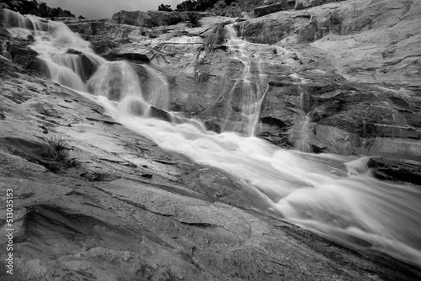 Fototapeta Beautiful Ghatkhola waterfall having full streams of water flowing downhill amongst stones , duriing monsoon due to rain at Ayodhya pahar (hill) - at Purulia, West Bengal, India. Black & White image.