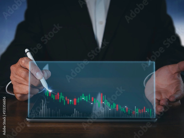 Fototapeta Businessman writing analyze graph for trade stock market on tablet screen. Businessman hand drawing chart graph stock of growth. Hand man uses pen to draw stock graph chart point of target success.