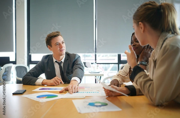 Fototapeta Image of young business people discussing document in paperwork data on desk at meeting