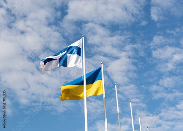 Fototapeta The flag of Ukraine and the Flag of Finland are flying in the sky. Assistance to Ukraine from Finland