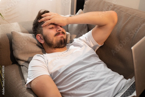 Fototapeta image fun et amusante d'un jeune homme allongé sur son canapé qui s'énerve à cause de son ordinateur portable. Il devient fou