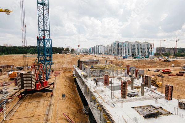 Fototapeta Construction site background. Hoisting cranes and new multi-storey buildings