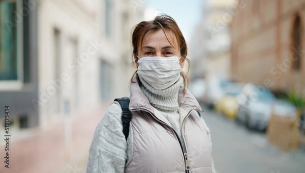 Fototapeta Middle age hispanic woman wearing medical mask at street