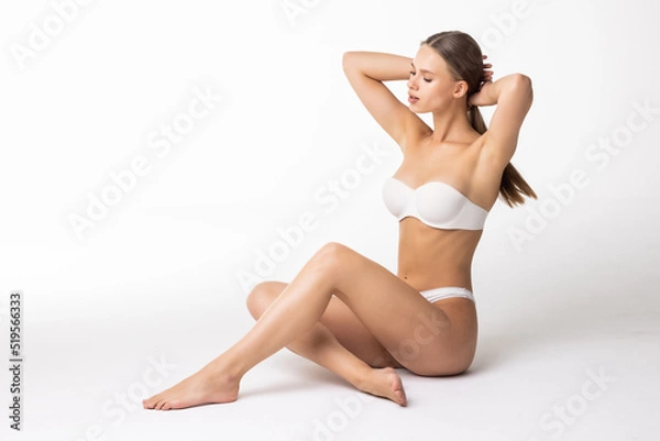 Fototapeta Young woman in cotton underwear sitting on white background