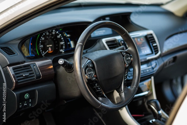 Fototapeta Black luxury modern car interior. Steering wheel, shift lever, speedometer, display, gearbox handle, and multimedia dashboard. Detail of car interior inside. Automatic gear stick.