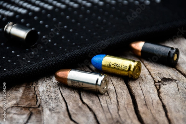 Fototapeta 9mm pistol bullets and bullet shells on wooden table, soft and selectivec focus.