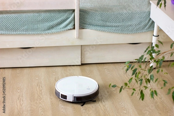 Obraz White robotic vacuum cleaner cleaning at home.