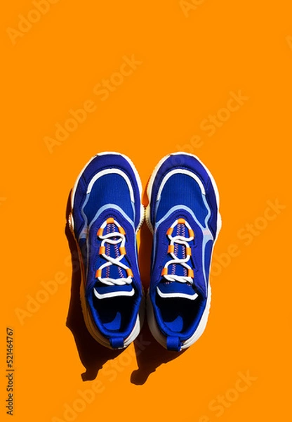 Fototapeta Blue sneakers on orange background. Trendy sport shoe, street casual footwear.