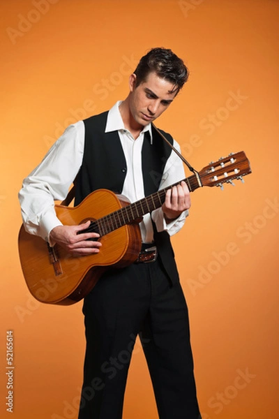 Fototapeta Retro country male guitar player wearing black suit. Studio shot