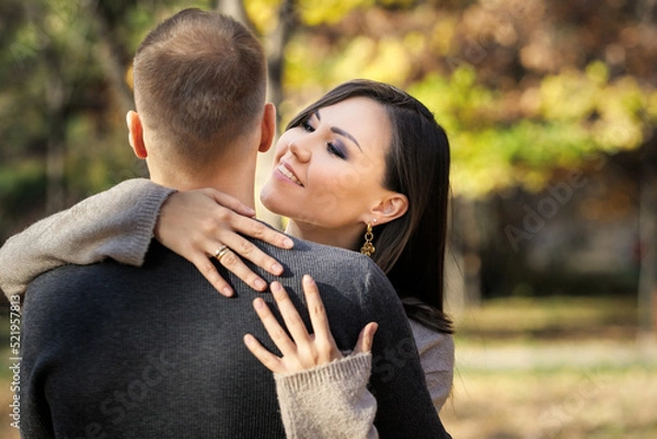 Fototapeta Beautiful young asian woman lovingly hugging her man in autumn park.