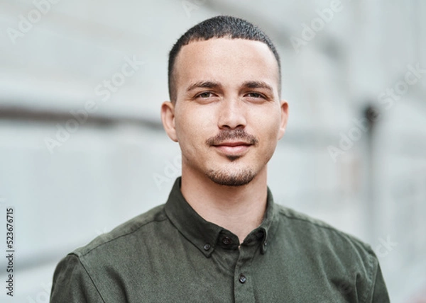 Fototapeta Closeup face of a serious, motivated and ambitious man standing outside in a city, town or downtown alone. Portrait, headshot and face of social worker or volunteer looking forward with trust or care