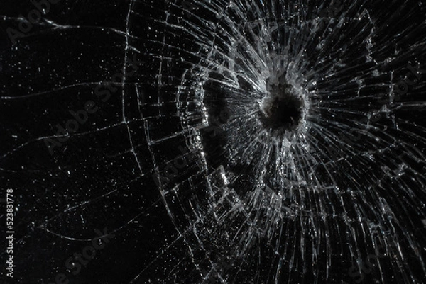 Fototapeta Bullet hole in a glass on the black background.closeup.