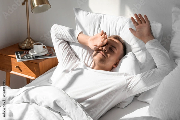 Fototapeta Young man waking up at home in morning