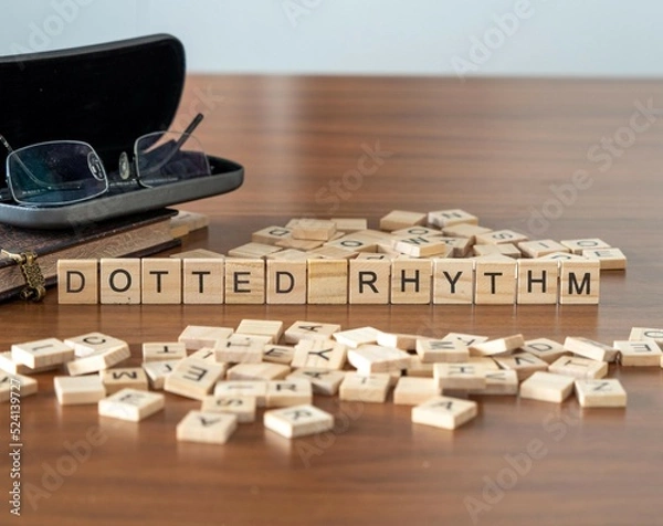 Fototapeta dotted rhythm word or concept represented by wooden letter tiles on a wooden table with glasses and a book