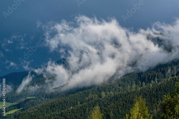 Fototapeta low hanging clouds and fog in the mountains at a summer day