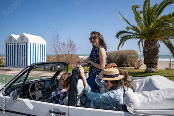 Fototapeta Five young women in a convertible car