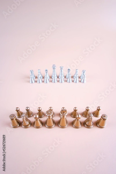 Fototapeta Gold and silver chess on a beige background.