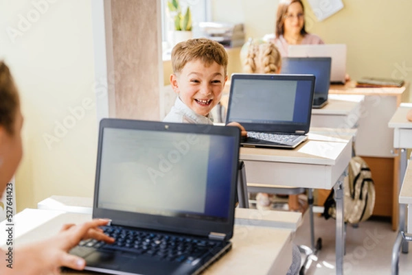 Fototapeta Cute smiling pupil boy during Informatics class. Internet technology. Modern education concept Modern education internet technologies concept.