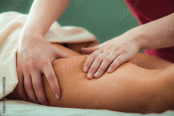 Fototapeta Relaxing legs massage, hands of a female massage therapist massaging female client’s legs