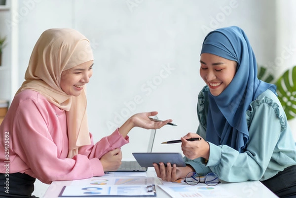 Fototapeta Two beautiful Muslim business woman wearing hijab talk and discuss accounting and finance. and cooperate with the marketing department Marketing and Investment Planning.