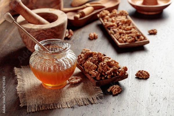 Fototapeta Honey and walnut on a old wooden table.