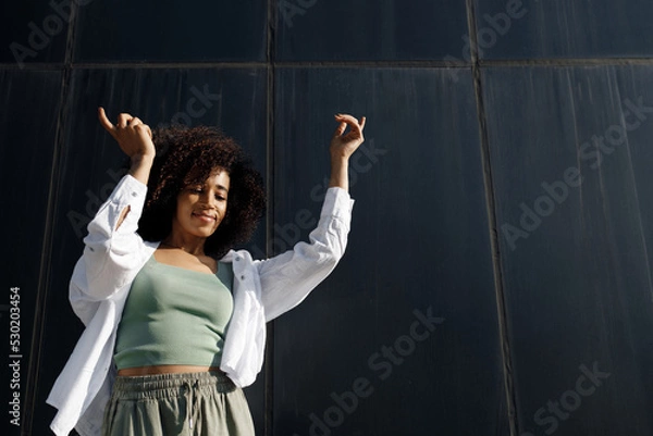 Fototapeta pretty smiling black woman dancing outdoors