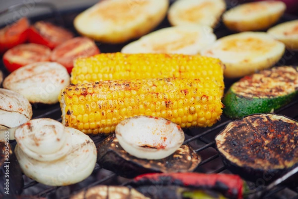 Fototapeta corn with paprika spice and vegetables is cooked on the grill