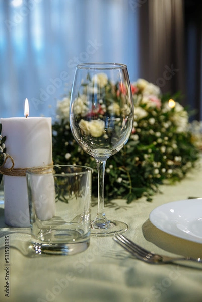 Fototapeta The table is decorated with plates and glasses with flowers on the table