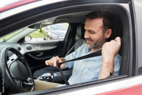 Fototapeta Caucasian man of middle age fasten seat belts in car