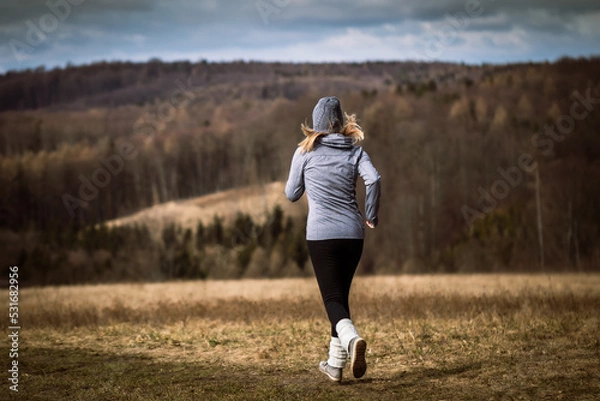 Fototapeta Woman running in autumn nature. Fitness activity outdoors