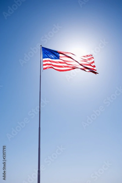 Fototapeta American flag blowing in clear blue sky.