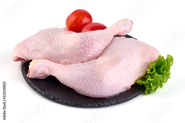 Fototapeta Raw chicken leg quarters on a stone plate, isolated on white background.