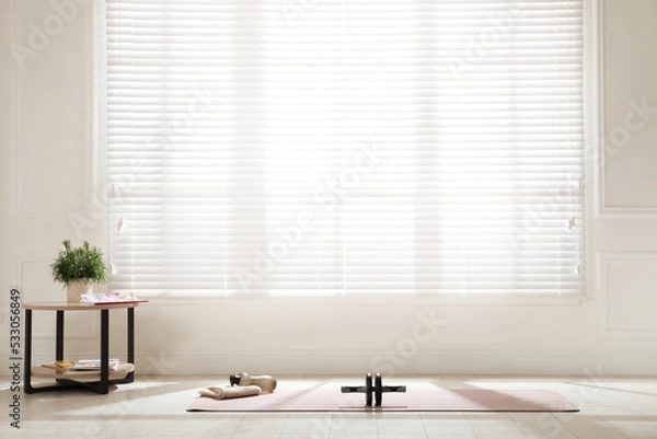 Fototapeta Exercise mat, ab roller, towel and bottle of water near window in spacious room