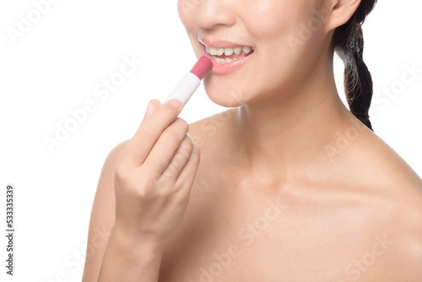 Fototapeta Portrait young asian woman looking mirror applying makeup lipstick at room