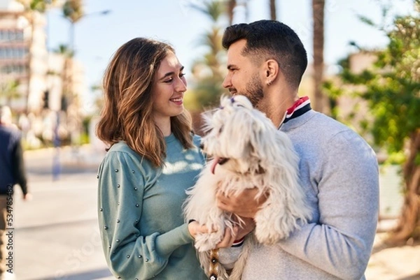 Fototapeta Man and woman holding dog standing together at park