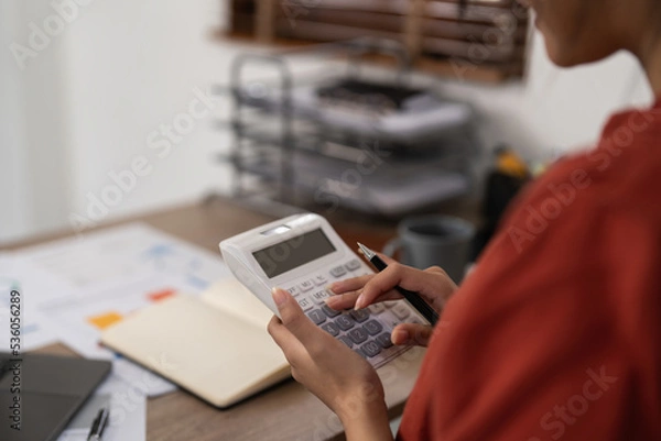 Fototapeta Asian Business woman calculating saving account balance with working at home, account and saving concept