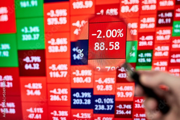 Fototapeta A trader looking at a stock heatmap through a magnifying glass