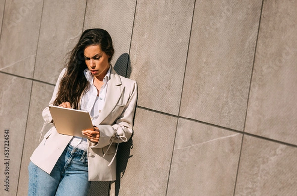 Fototapeta Portrait of a smiling business woman using digital tablet during quick break in front a corporate building.