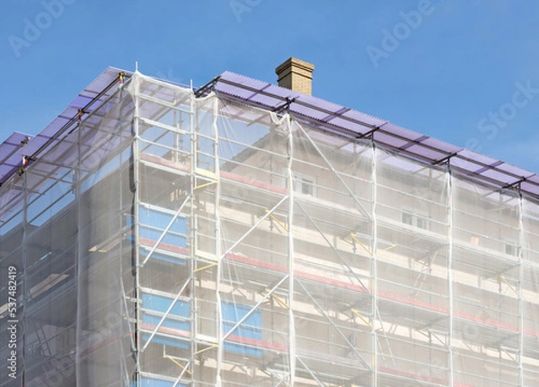 Fototapeta Scaffolding on house facade, apartment builing under construction