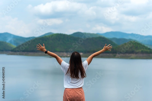 Fototapeta Woman rise her hands up to sky with mountain and water in Chiangmai Thailand for freedom, success and travel concept.