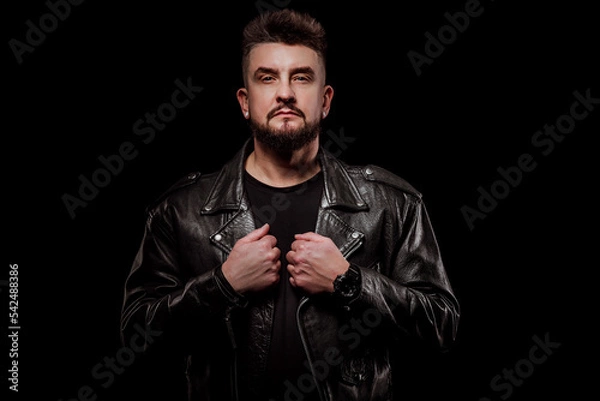 Fototapeta portrait of a man in a leather jacket and in the studio on a black background