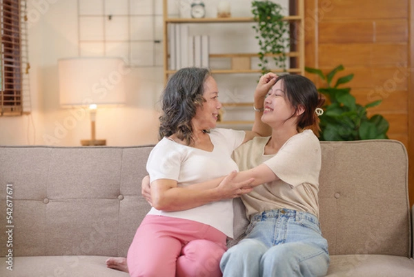 Fototapeta Mother-daughter Asian women spend their holidays in the living room expressing their love at home happily and warmly.