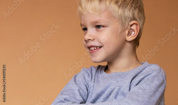 Fototapeta A boy with a hearing aids on beige background