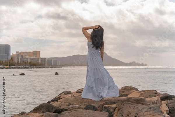 Fototapeta Beautiful shot of a woman in a long dress posing in Honolulu, Hawaii