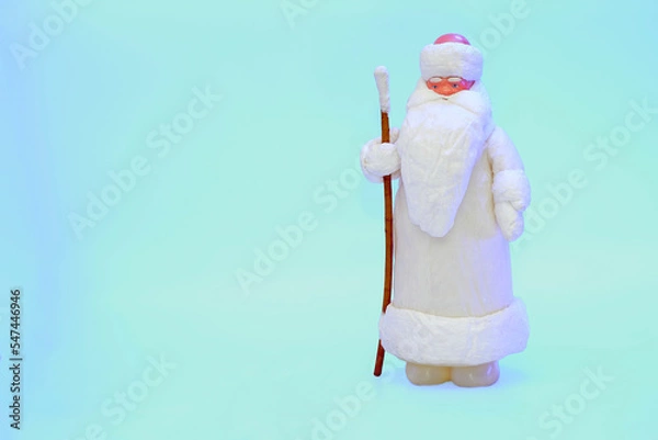 Fototapeta Santa claus with staff in white fur coat isolated on snow blue