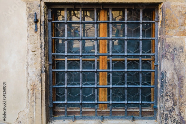 Fototapeta Ground floor window with wrought iron bars. Background or backdrop. Detail or element of classic retro vintage exterior