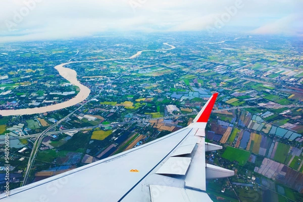 Fototapeta Beautiful aerial view of Bangkok, Thailand from window of a plane descending for landing overlooking the Chao Phraya River. Green areas of the city and roads. Airplane travel photography ideas