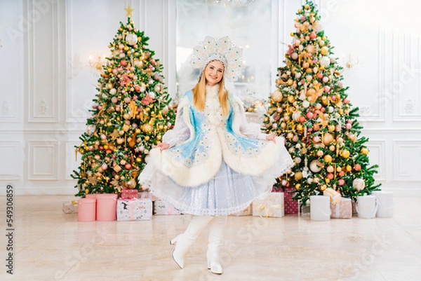 Fototapeta Snow Maiden in costume with short skirt and kokoshnik. room with christmas tree.