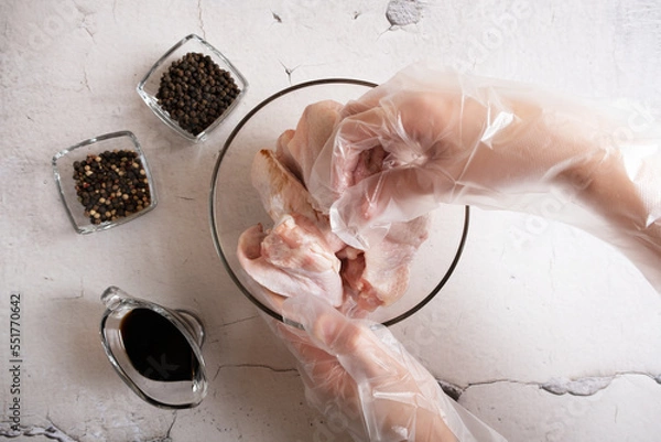 Fototapeta Gloved hands stir the wings with soy baking sauce. A dish of Asian cuisine.